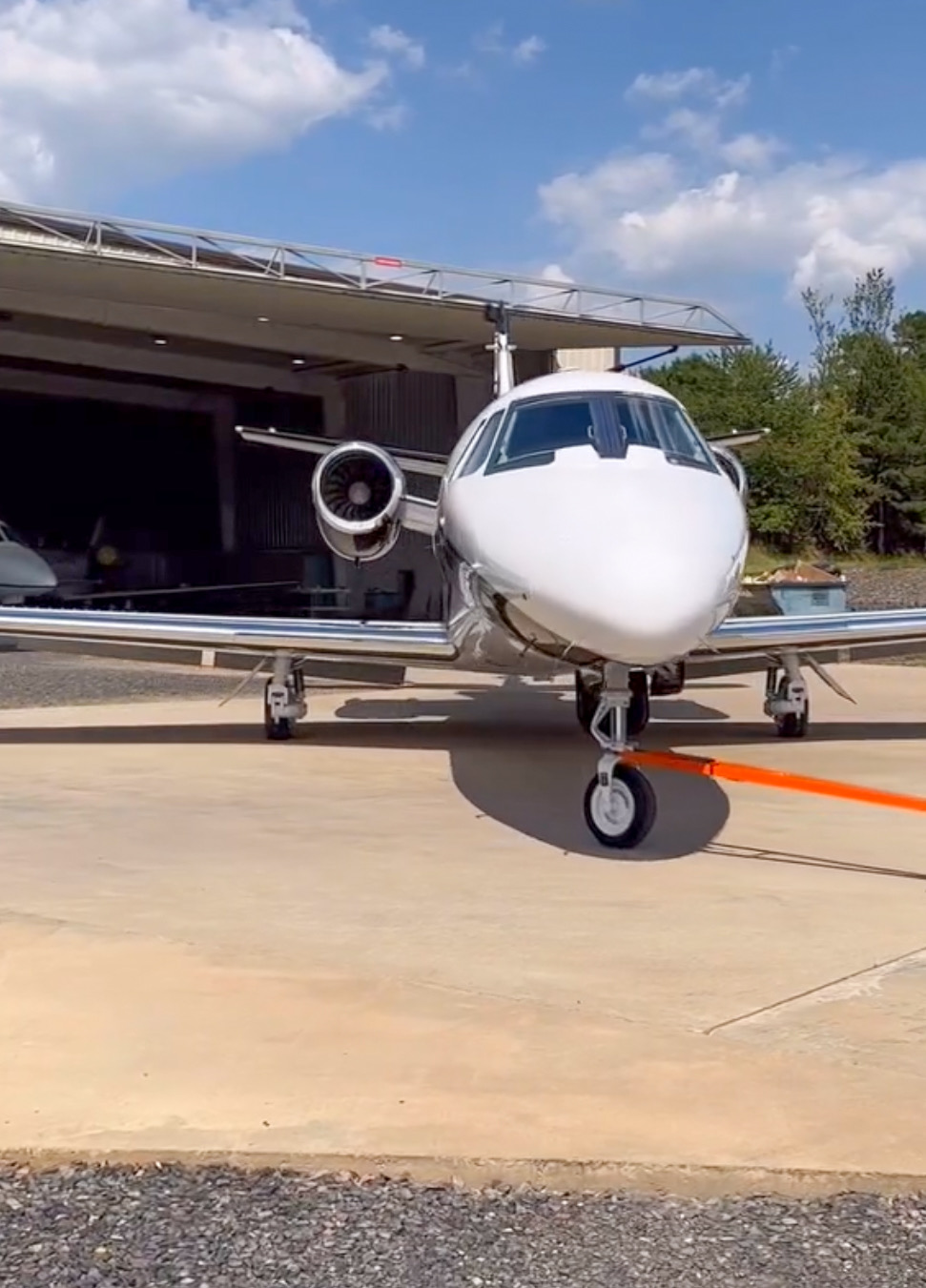 Business jet photographed from a centered front-on position outside a hangar