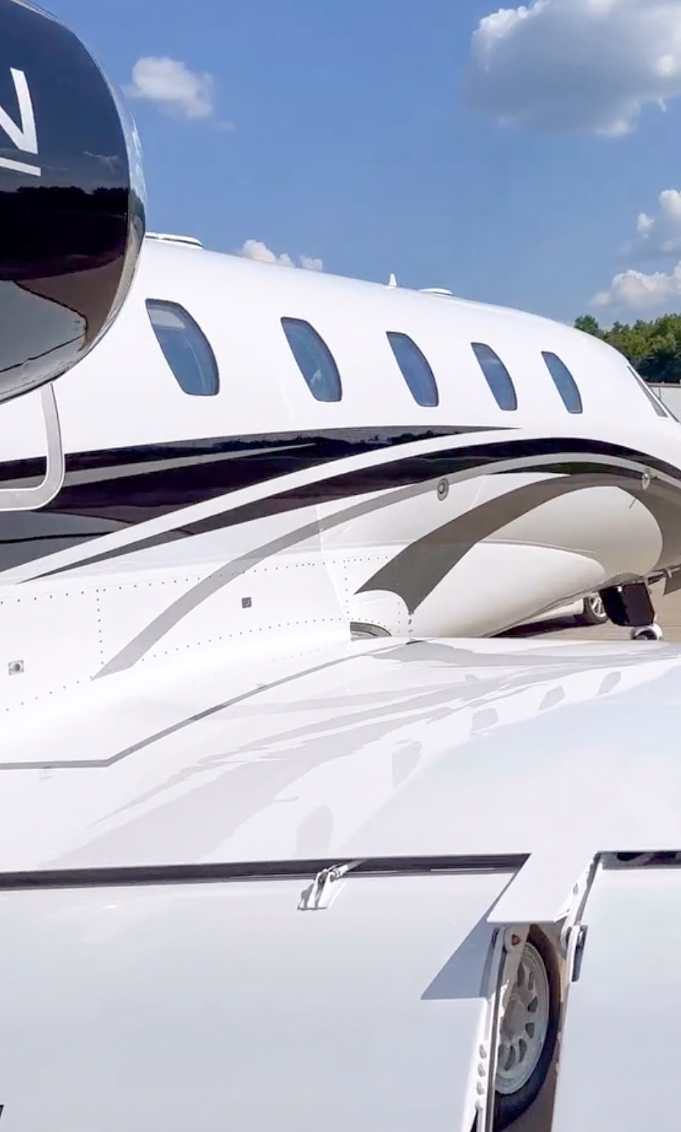 Close view of glossy white aircraft paint, cabin windows and sweeping fuselage graphics