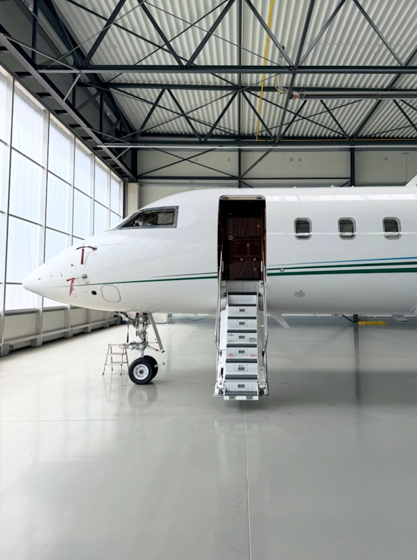 White business aircraft inside a hangar beside a large translucent wall