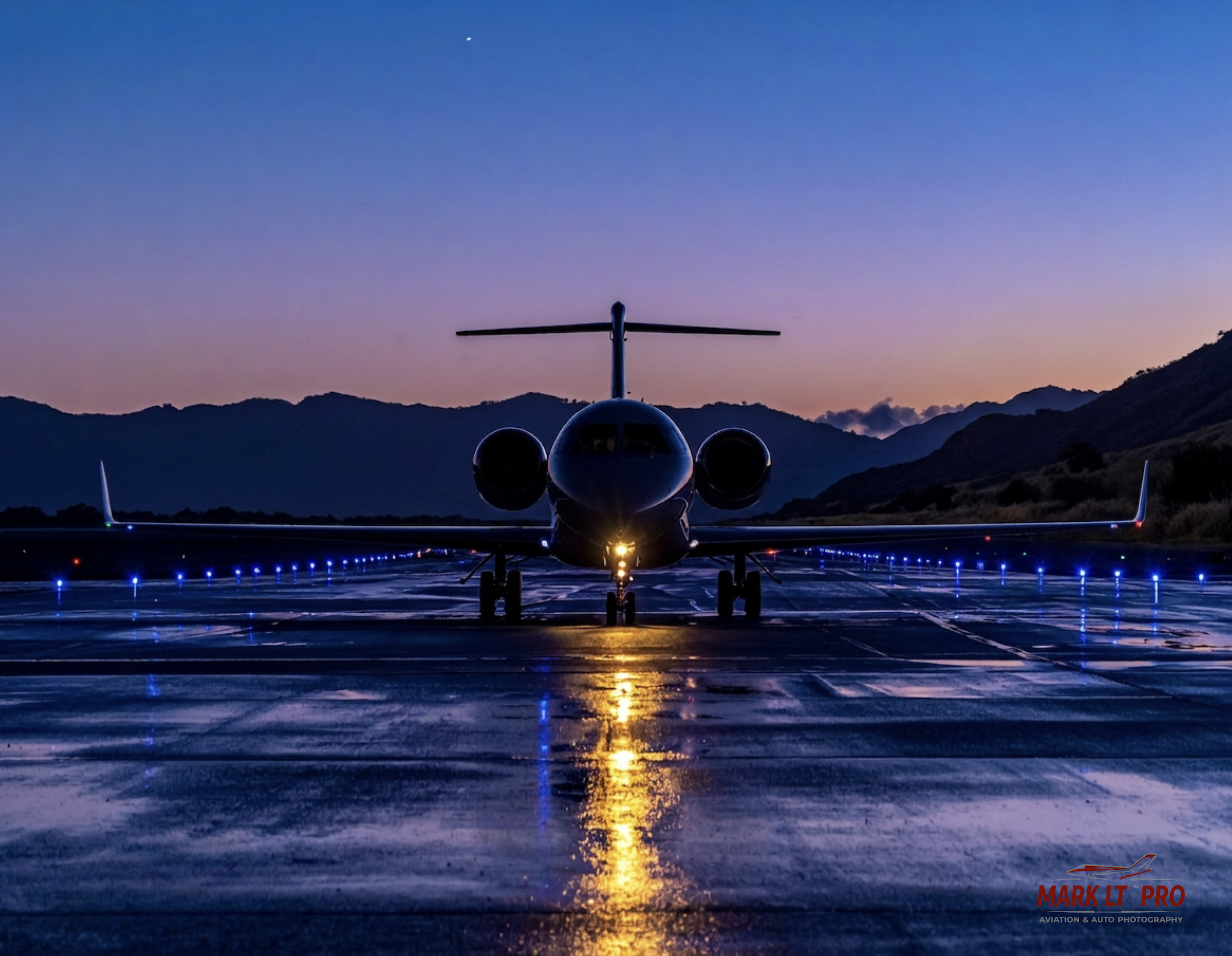 Business jet photographed head-on during blue hour on a wet illuminated ramp
